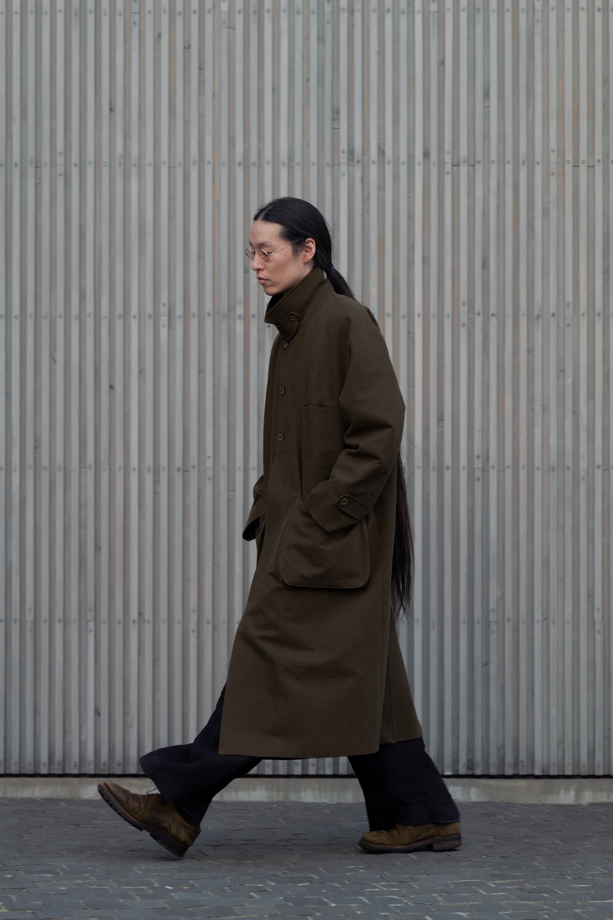 Perfil de la modelo caminando con el Aviva Jifei Xue Relaxed Mac Coat con el cuello levantado