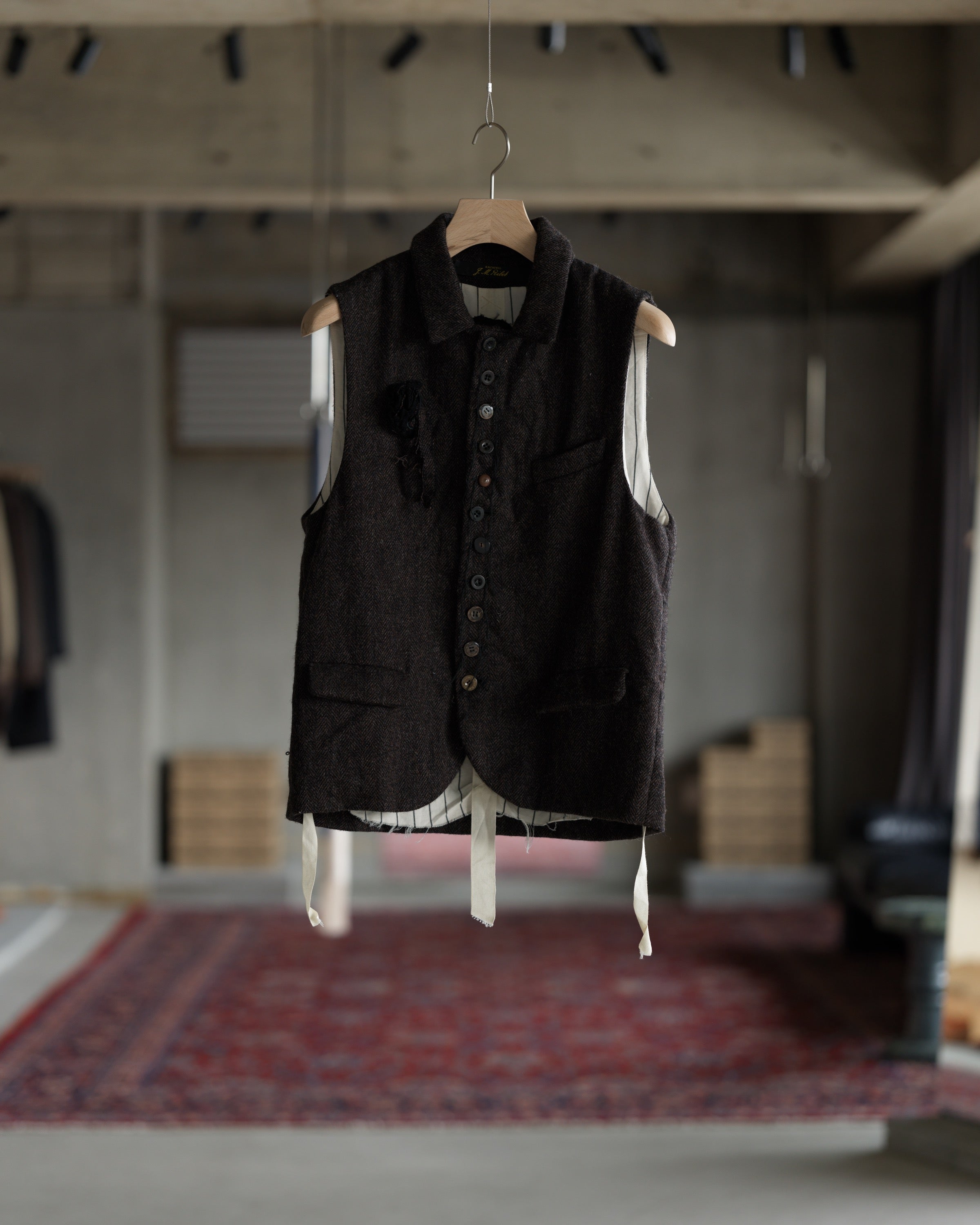 ハンガーにかかった ARCHIVIO J.M. Ribot の GL23 / FXM（Dark Brown Herringbone） 正面 やや引きのカット